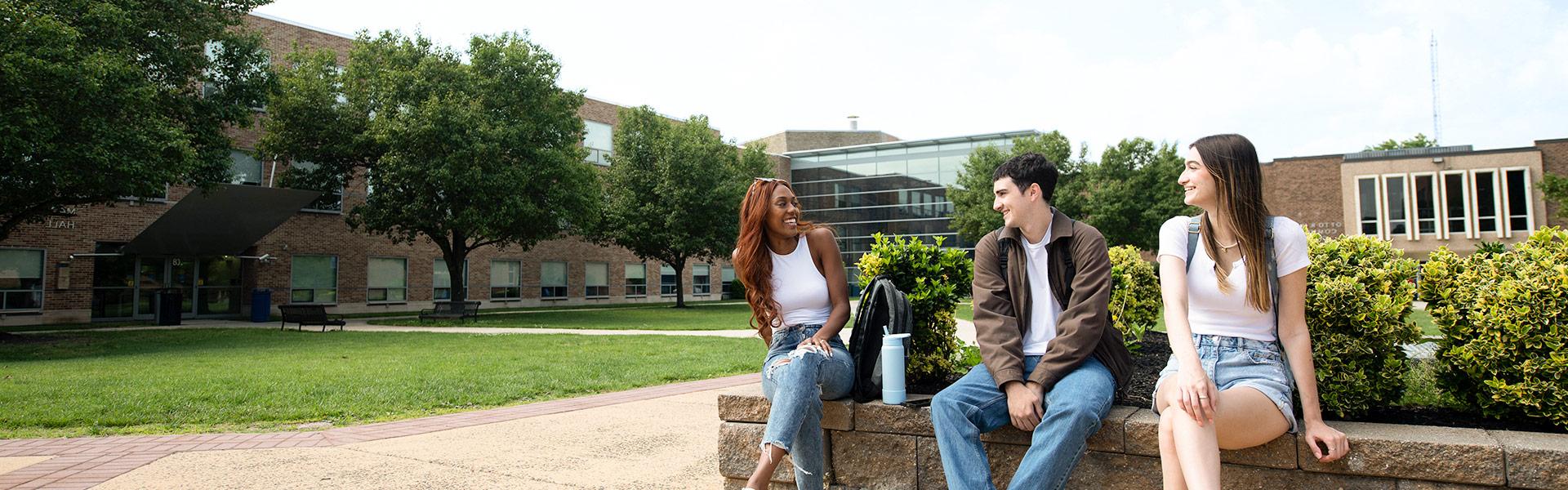 a group of 3 diverse students sitting in the courtyard of Camden County College's Blackwood Campus