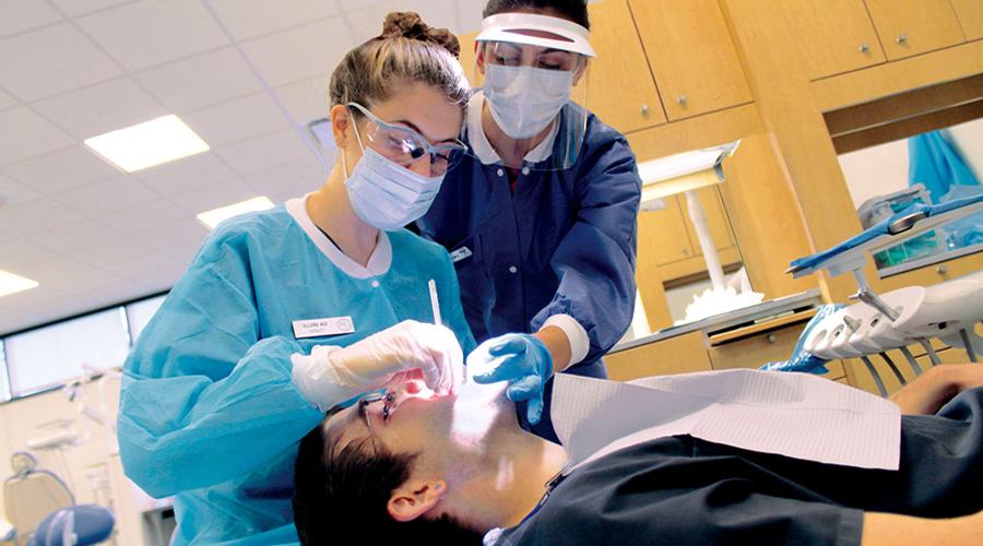Camden County College dental students cleaning a patients teeth